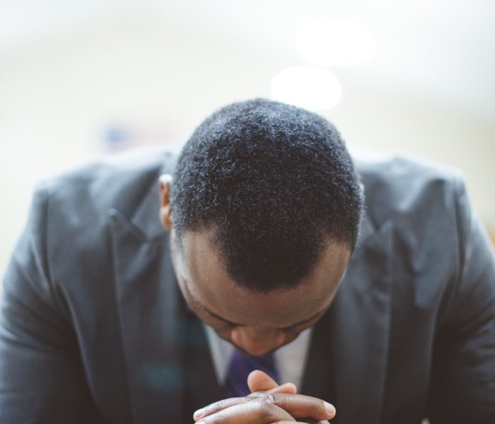 lonely-african-american-male-praying-with-his-hands-bible-with-his-head-down